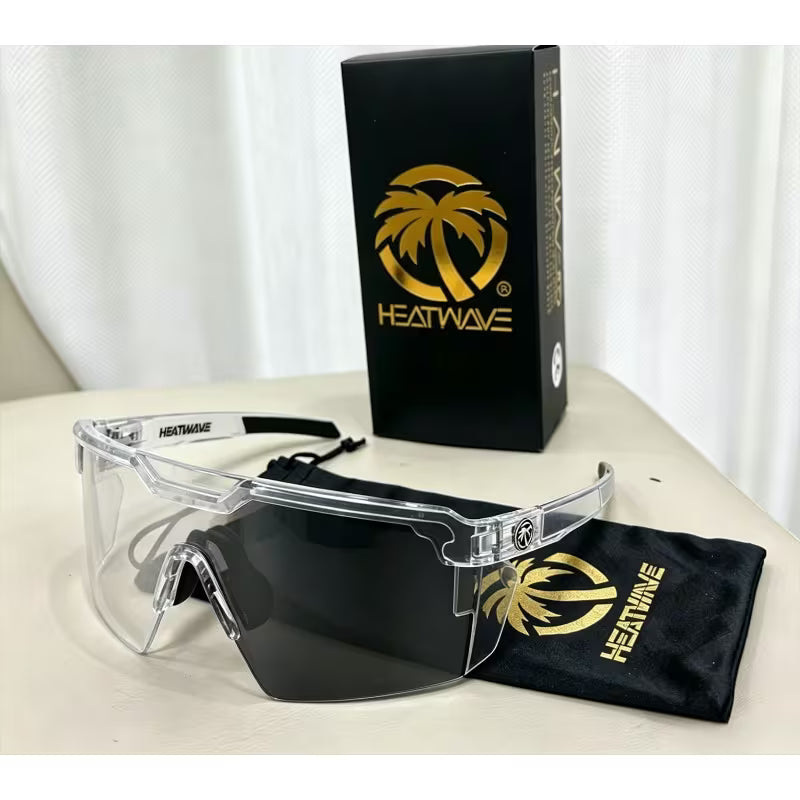 Clear shield-style safety glasses with a dark tinted lens, shown with a black Heatwave box, black storage pouch, and a small black Heatwave case on a light surface.