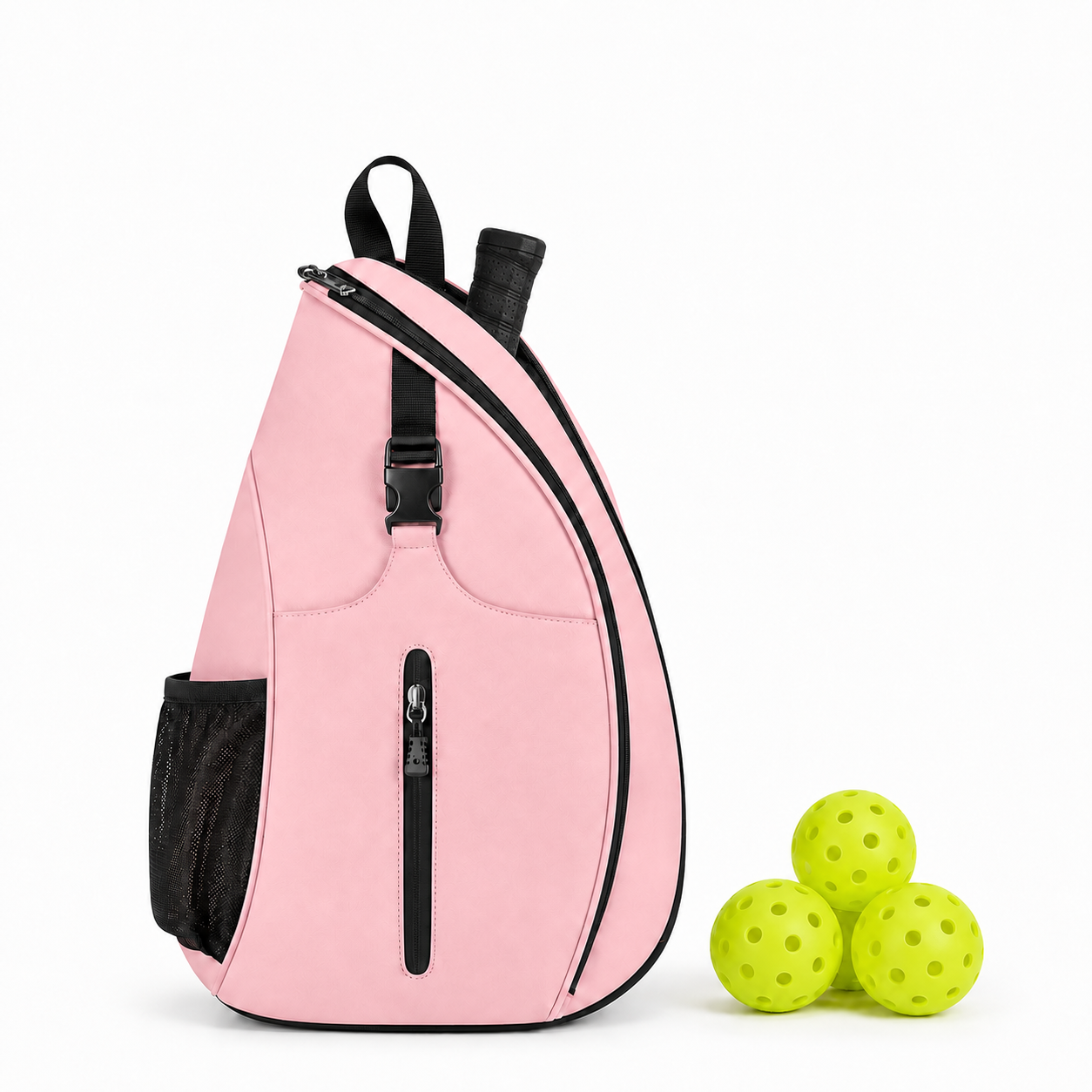 A pink teardrop-shaped sling backpack with black trim and straps, shown next to three lime green perforated pickleball balls on a clean white background.