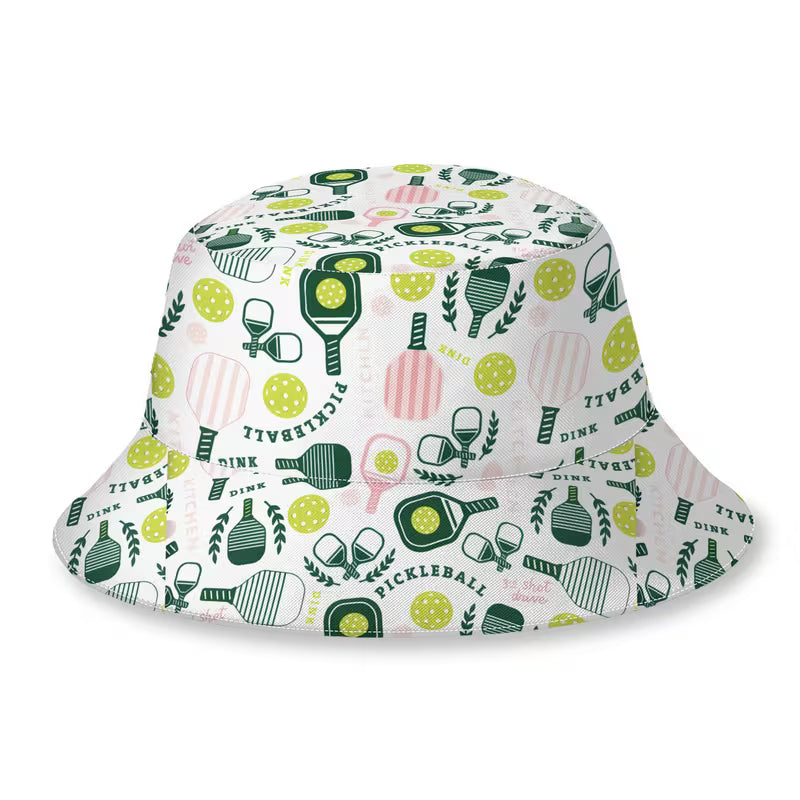 A white bucket hat featuring a colorful pickleball-themed pattern with green paddles, yellow balls, pink striped rackets, and green leaves, shown on a plain white background.
