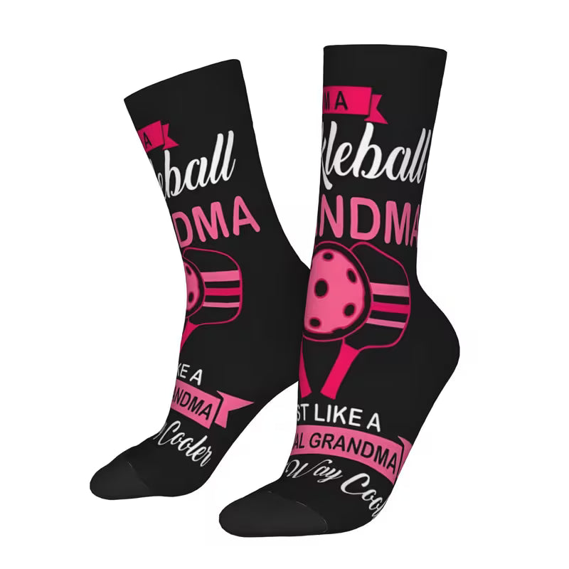 A pair of black crew socks with a pink and white graphic design featuring a softball bat and the text 'A Baseball Grandma Just Like a Cool Grandma'.