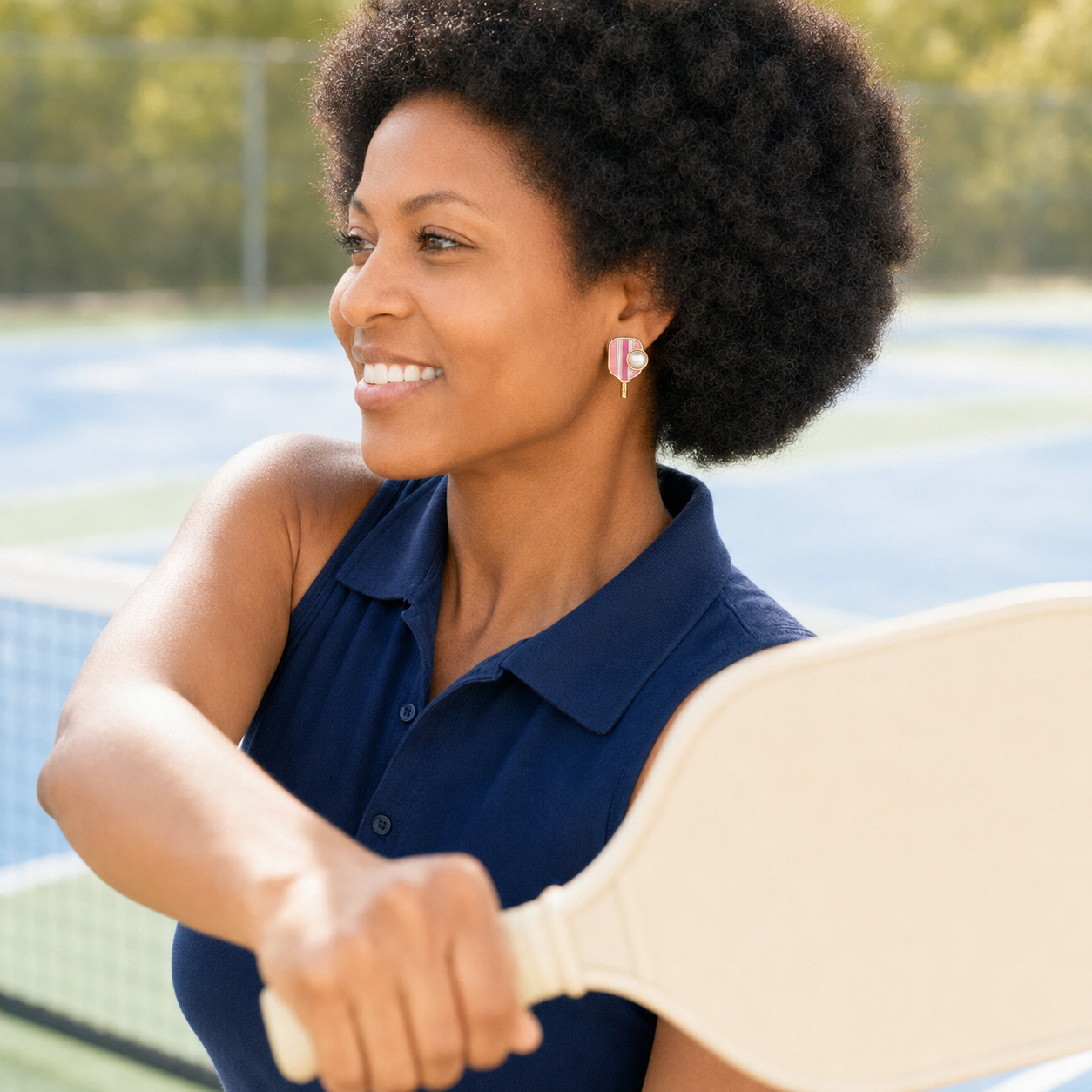 Woman wearing pink pickleball enamel and pearl earrings