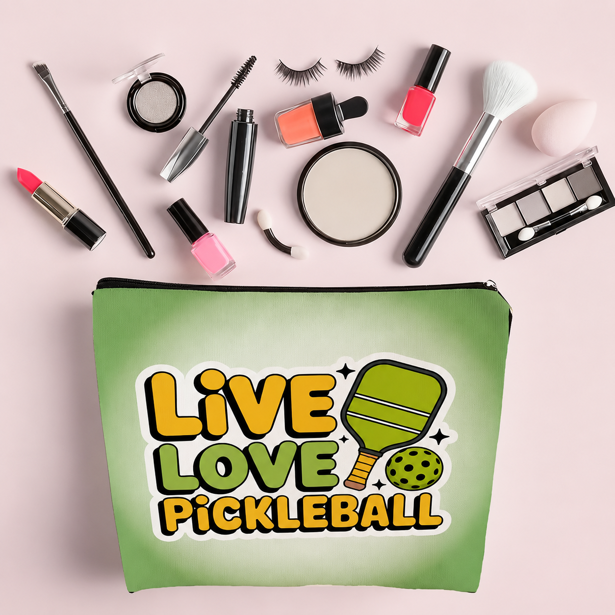 A green cosmetic pouch with a 'Live Love Pickleball' graphic, surrounded by various makeup items on a light pink background.