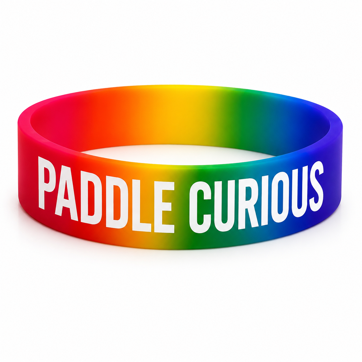 A silicone wristband featuring a vibrant rainbow gradient with the words 'PADDLE CURIOUS' printed in bold white capital letters, shown on a clean white background.
