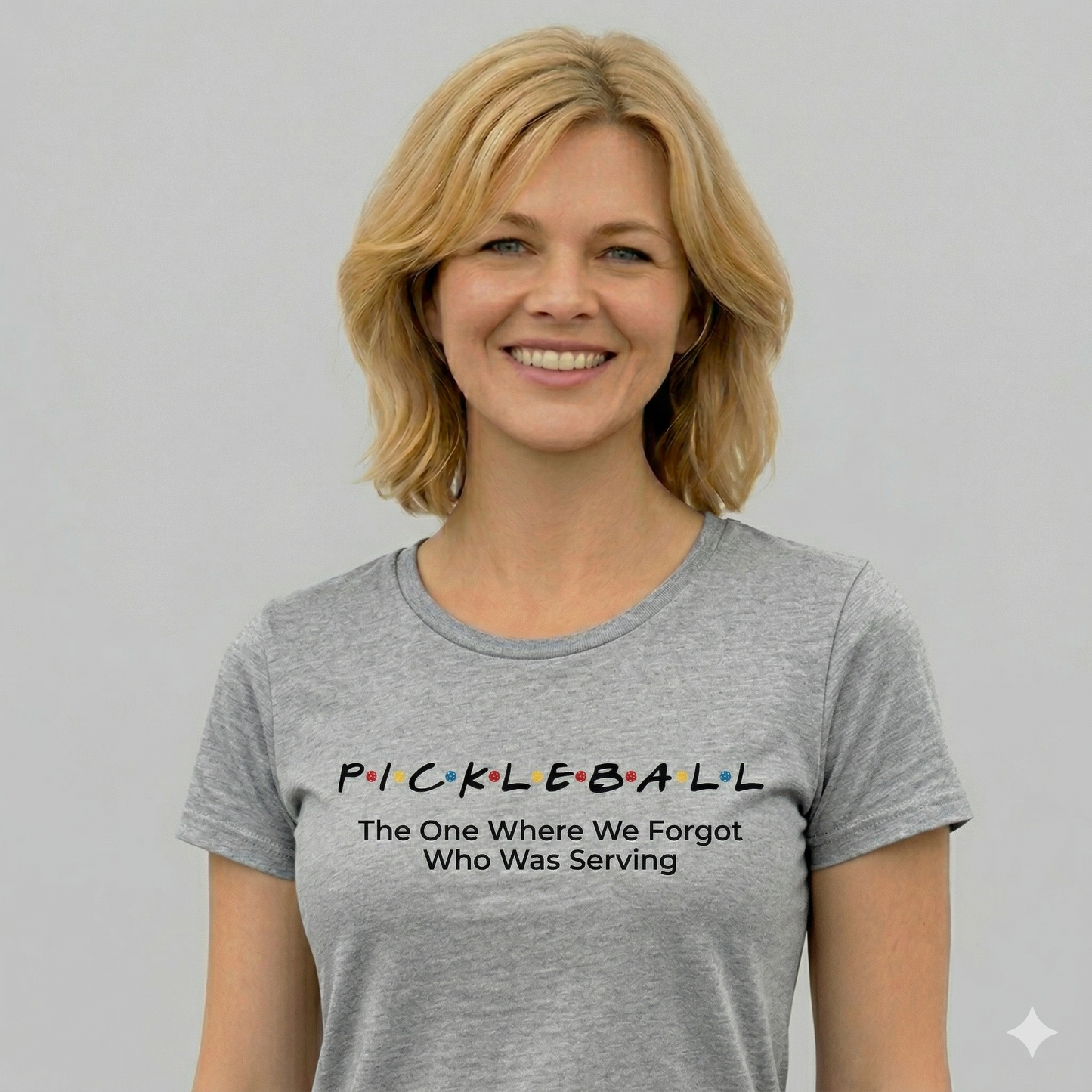 Woman wearing a gray t-shirt with a humorous pickleball quote on a plain background