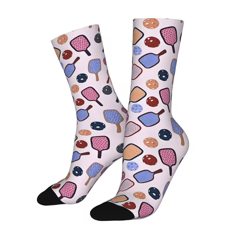 A pair of crew socks with a colorful retro pattern of ping-pong paddles and balls on a white background, featuring black toe and heel caps.