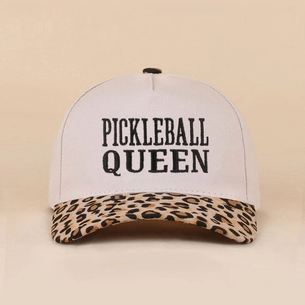 A white structured baseball cap with black text reading 'PICKLEBALL QUEEN' on the front and a leopard-print brim, shown against a plain beige background. The brand name 'LEOPARD' appears in the bottom right corner.
