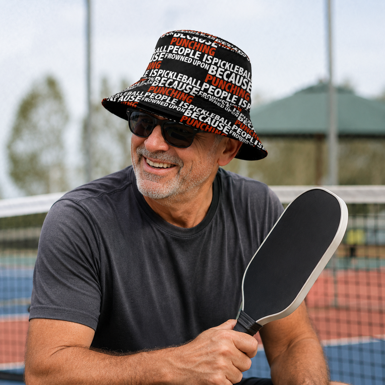 Man wearing funny pickleball bucket hat courtside with a pickleball paddle
