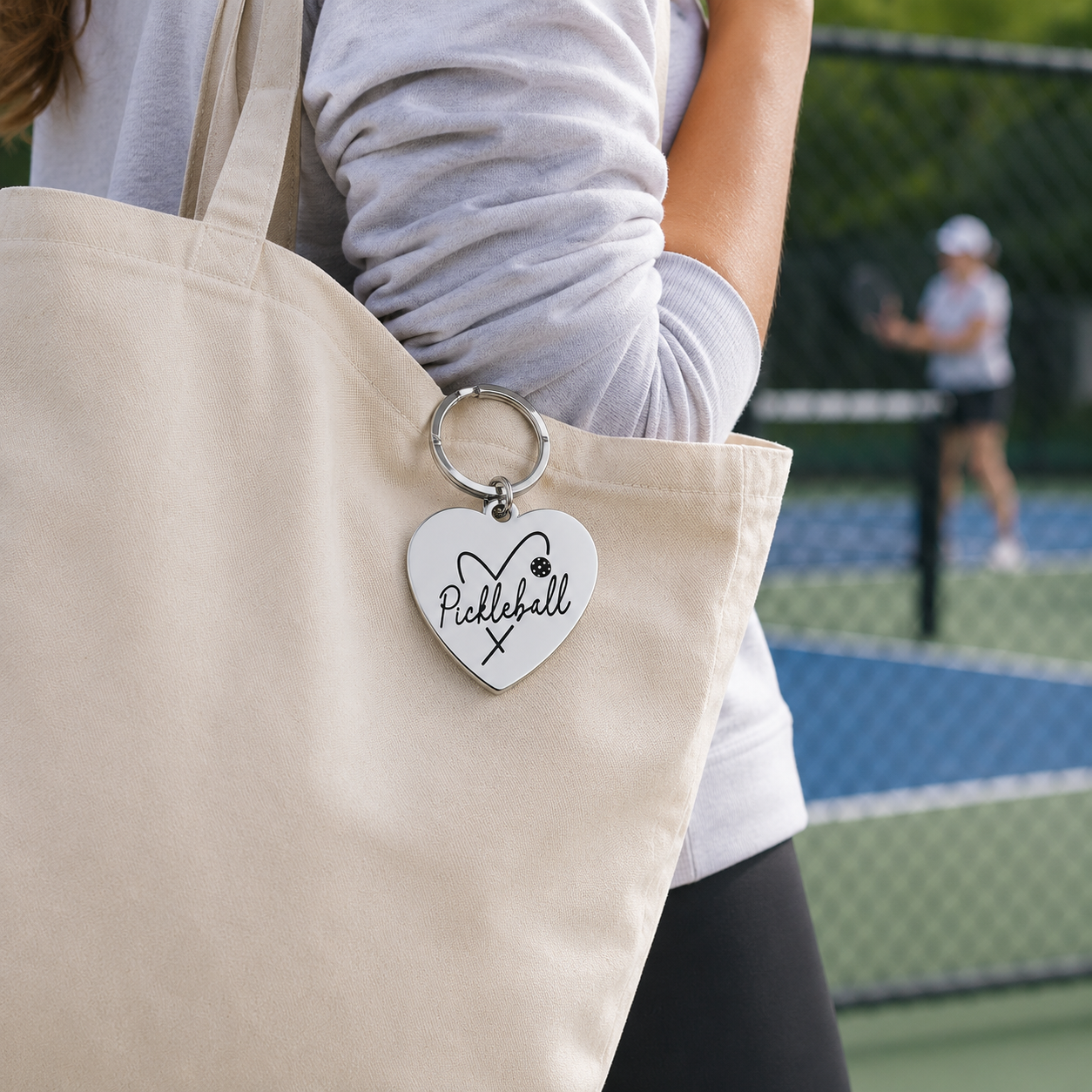 LOVE Pickleball engraved keychain attached to a canvas tote at a pickleball court