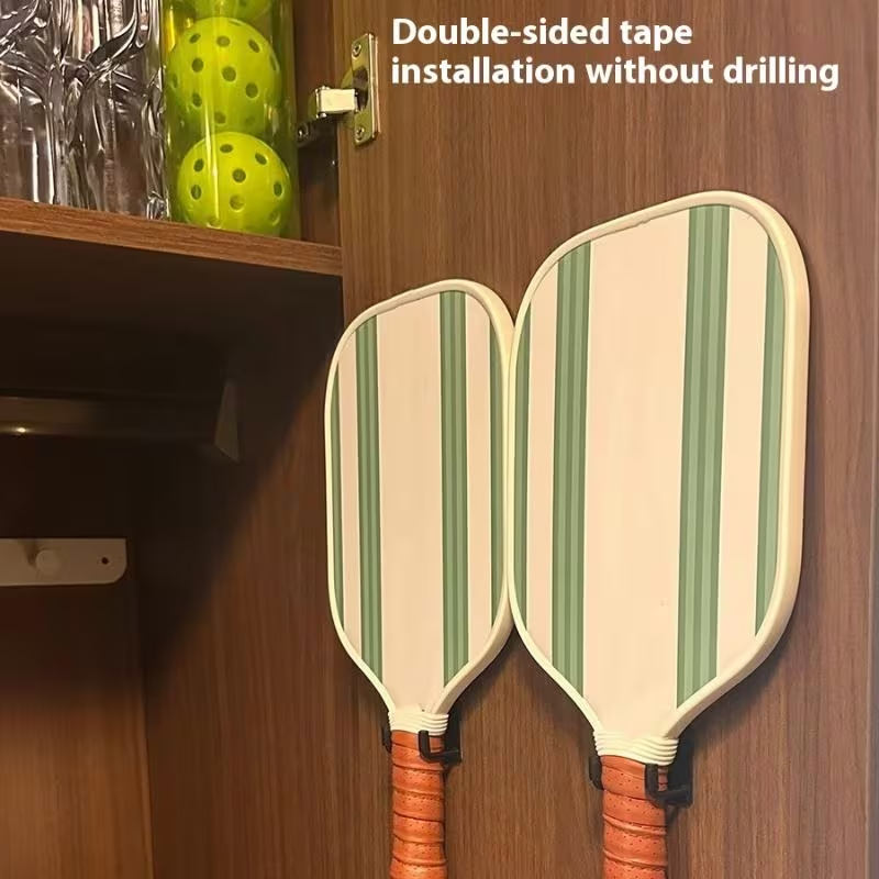 Pickleball paddles stored with wall-mounted racks installed using double-sided tape
