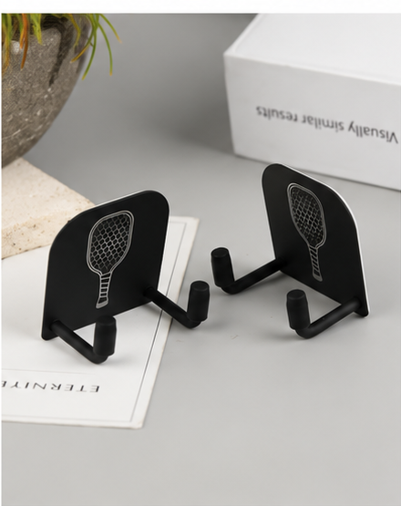 Two black wall-mounted pickleball paddle racks shown on a tabletop